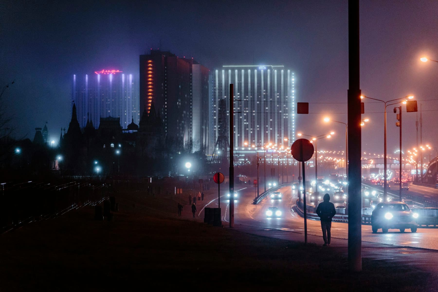 City skyline at night with illuminated high rise buildings and traffic light trails