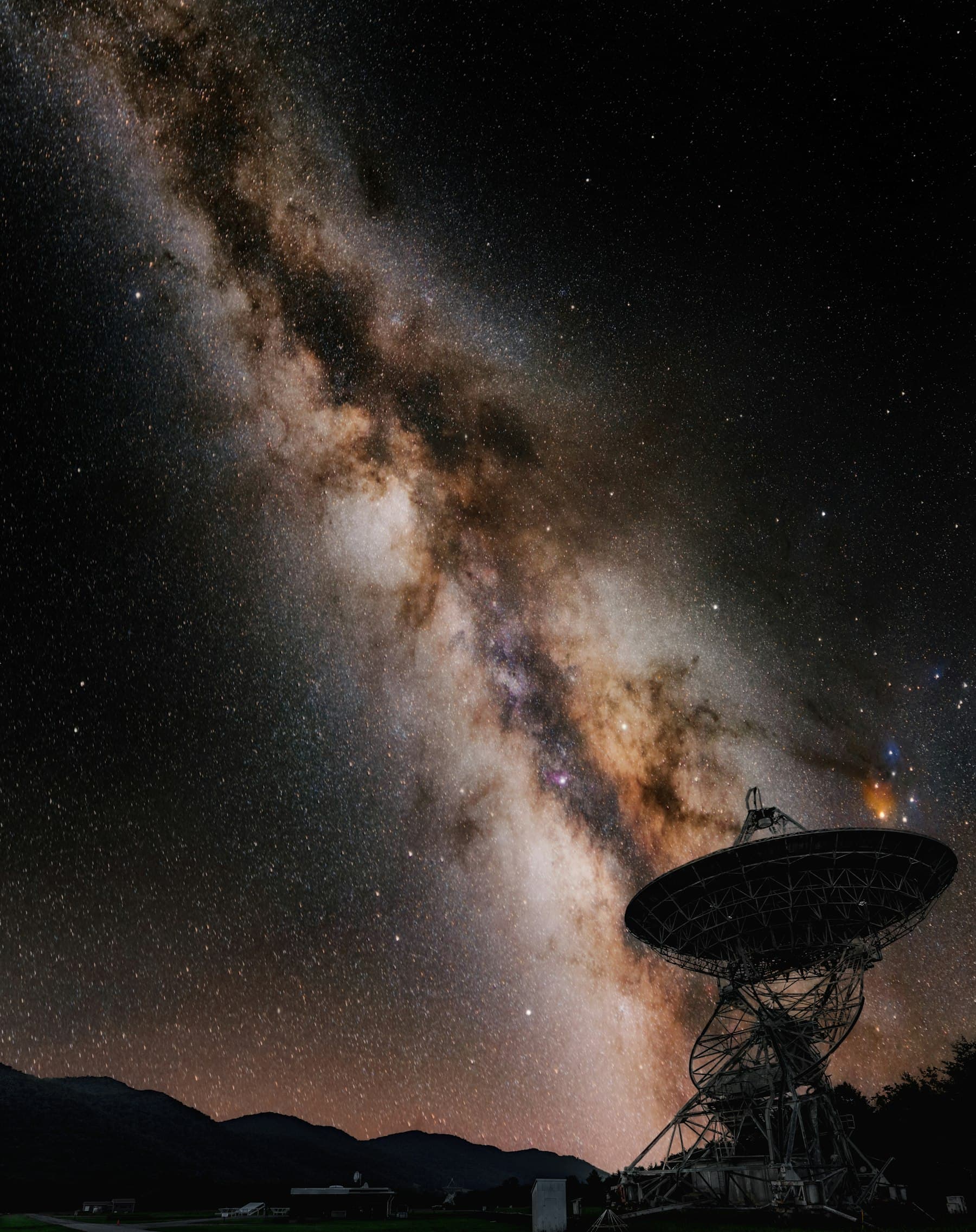 A satellite ground station dish silhouetted against the night sky