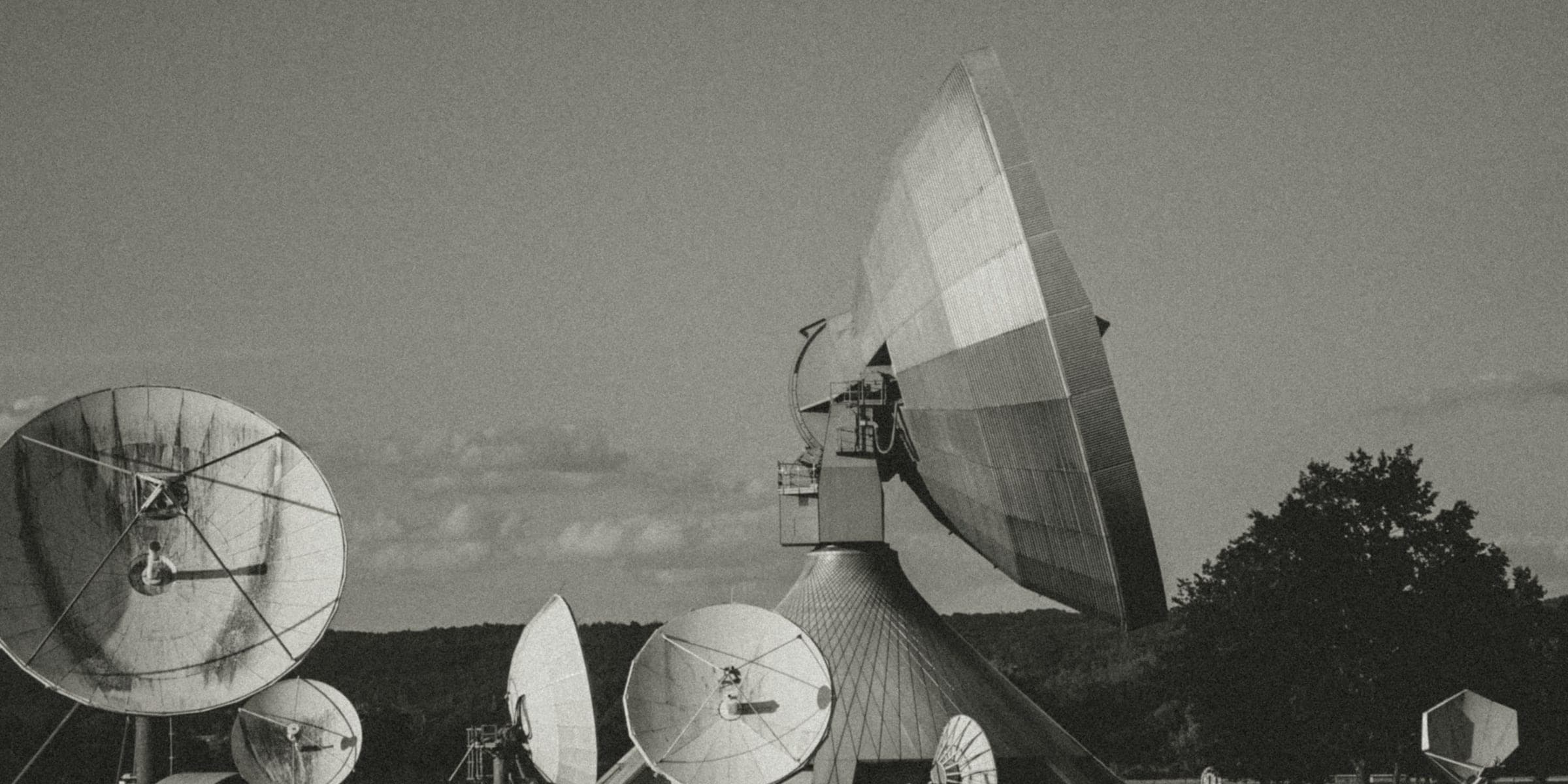 Large aperture tracking antenna and a field of smaller dishes at a satellite ground station