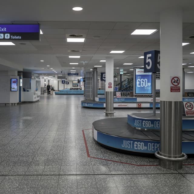A baggage reclaim hall with two carousels and their conveyor runs, seen from the concourse floor